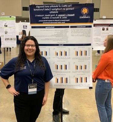 研究生 student stands in front of her poster presentation.